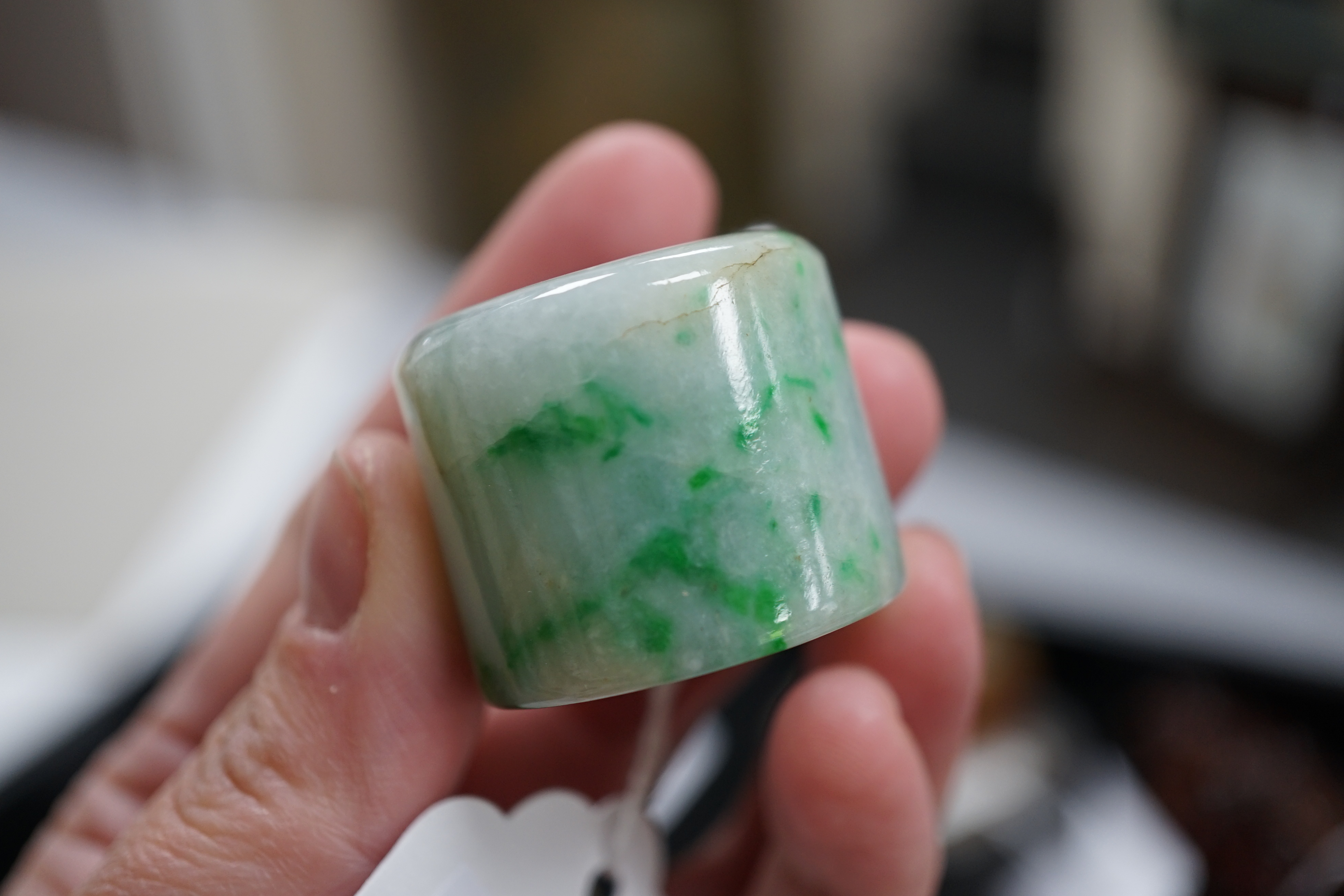 A Chinese jadeite archer's thumb ring, wood stand and cover, 19th century
